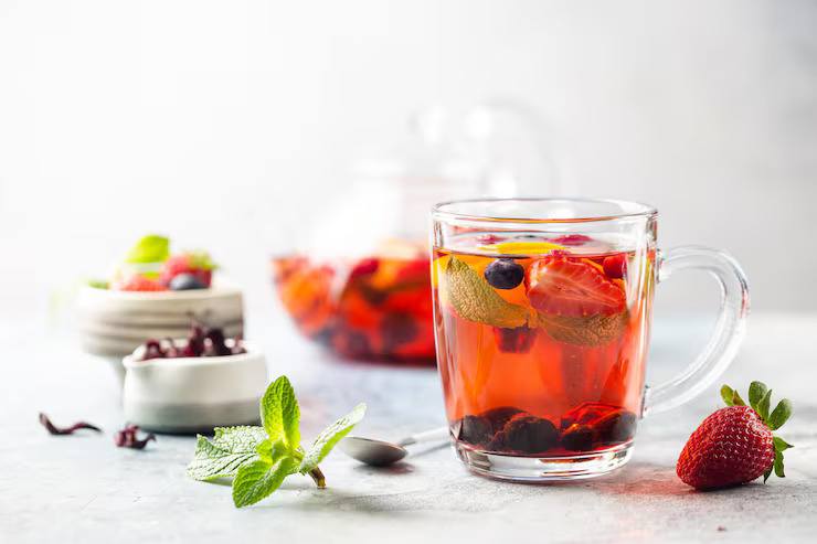 Fruit-infused iced tea in a clear glass mug with berries, mint leaves, and fresh fruits, showcasing a healthy flavoured iced tea.