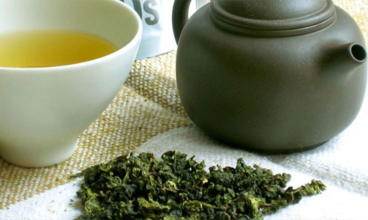 Loose Panda Dung Tea leaves with a ceramic teapot and cup showing traditional Chinese tea brewing.