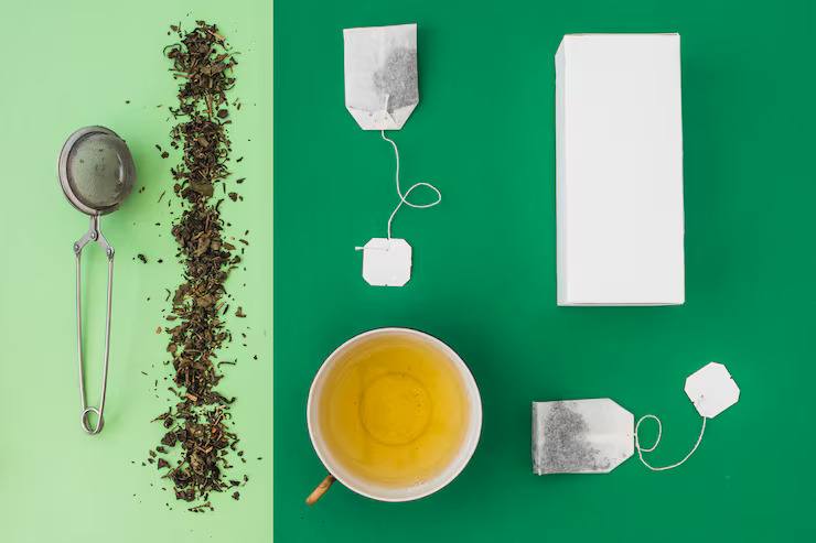 Flat lay of loose leaf tea and tea bags with a cup of brewed tea, tea infuser, and packaging, highlighting loose tea vs tea bags for everyday brewing.